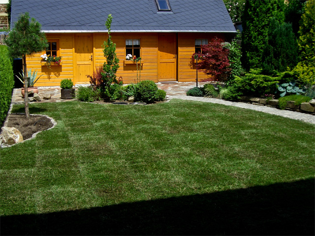 Referenzbild: 33 Terrasse aus Natursteinpflaster in Kombination mit Polygonalen Platten, umrahmt von Inselbeeten und einer großzügigen Lümmelwiese aus Rollrasen