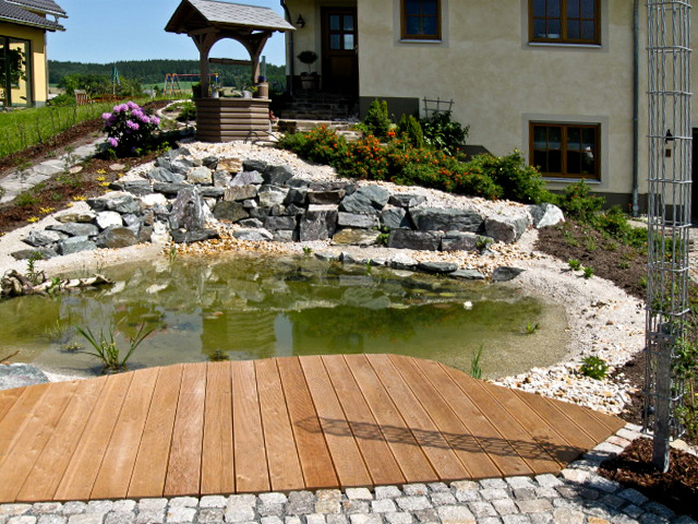 Referenzbild: 61 Eine kleine Terrasse aus Natursteinpflaster in Verbindung mit einem Holzsteg lädt zum Verweilen ein.