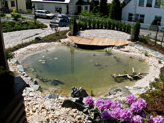 Referenzbild: 62 Eine kleine Terrasse aus Natursteinpflaster in Verbindung mit einem Holzsteg lädt zum Verweilen ein.